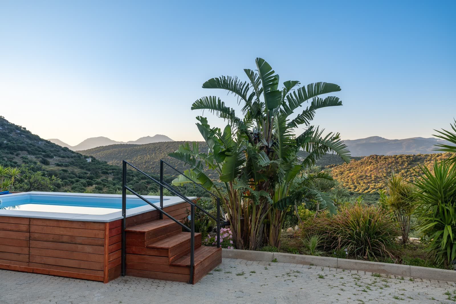 Sunset over the pool — the steps, the banana palms and the hills turning gold
