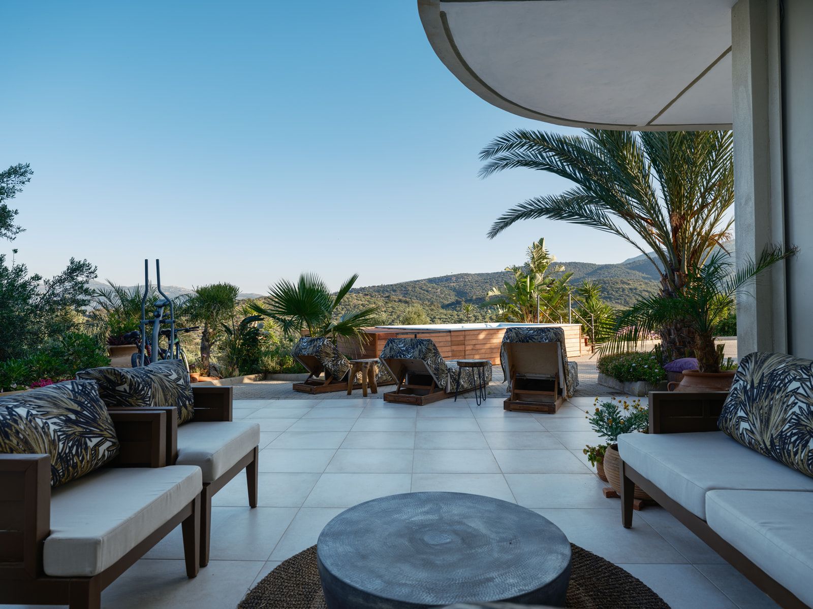 Golden-hour light on the terrace, palms overhead and hills beyond