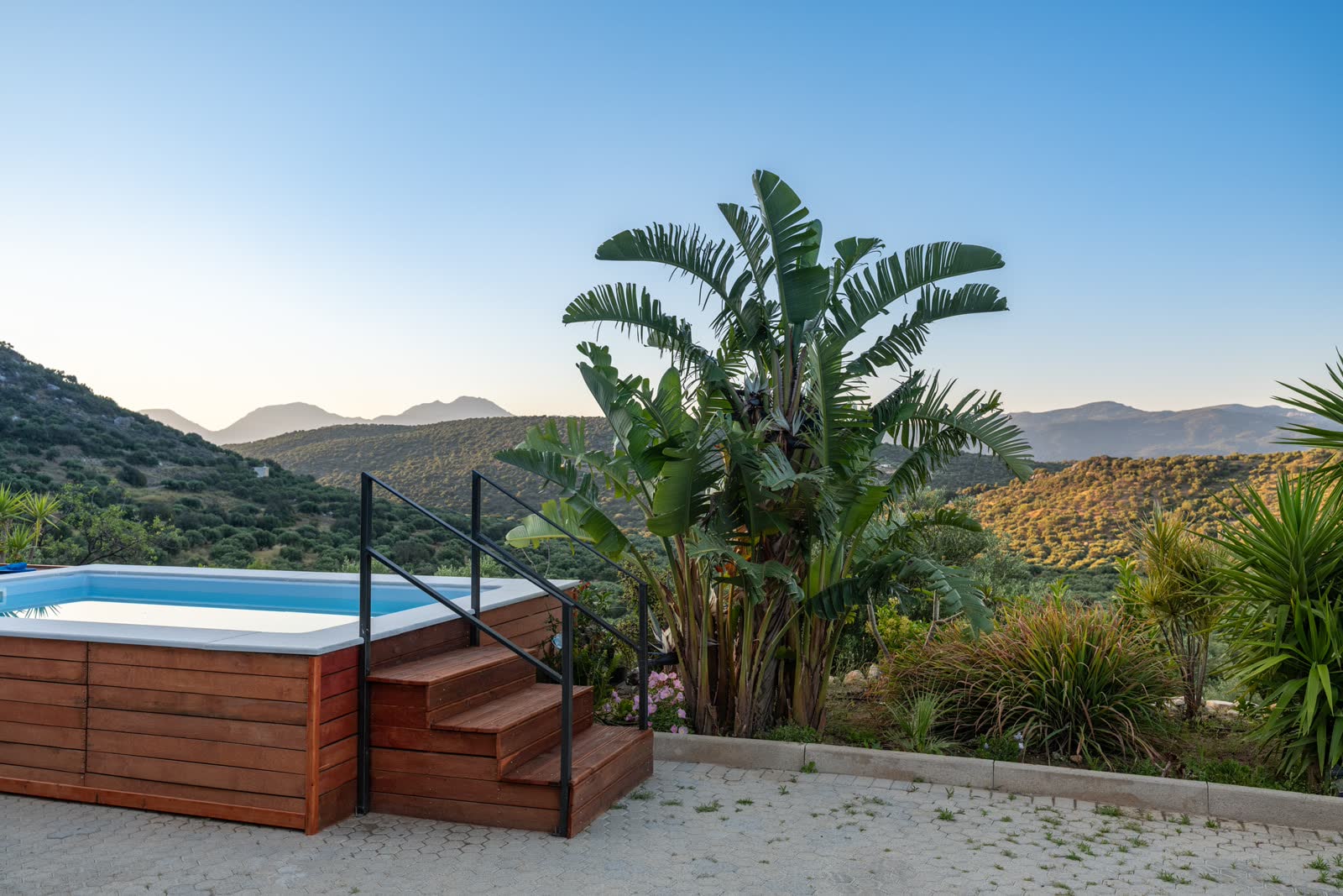 Sunset over the pool — the steps, the banana palms and the hills turning gold