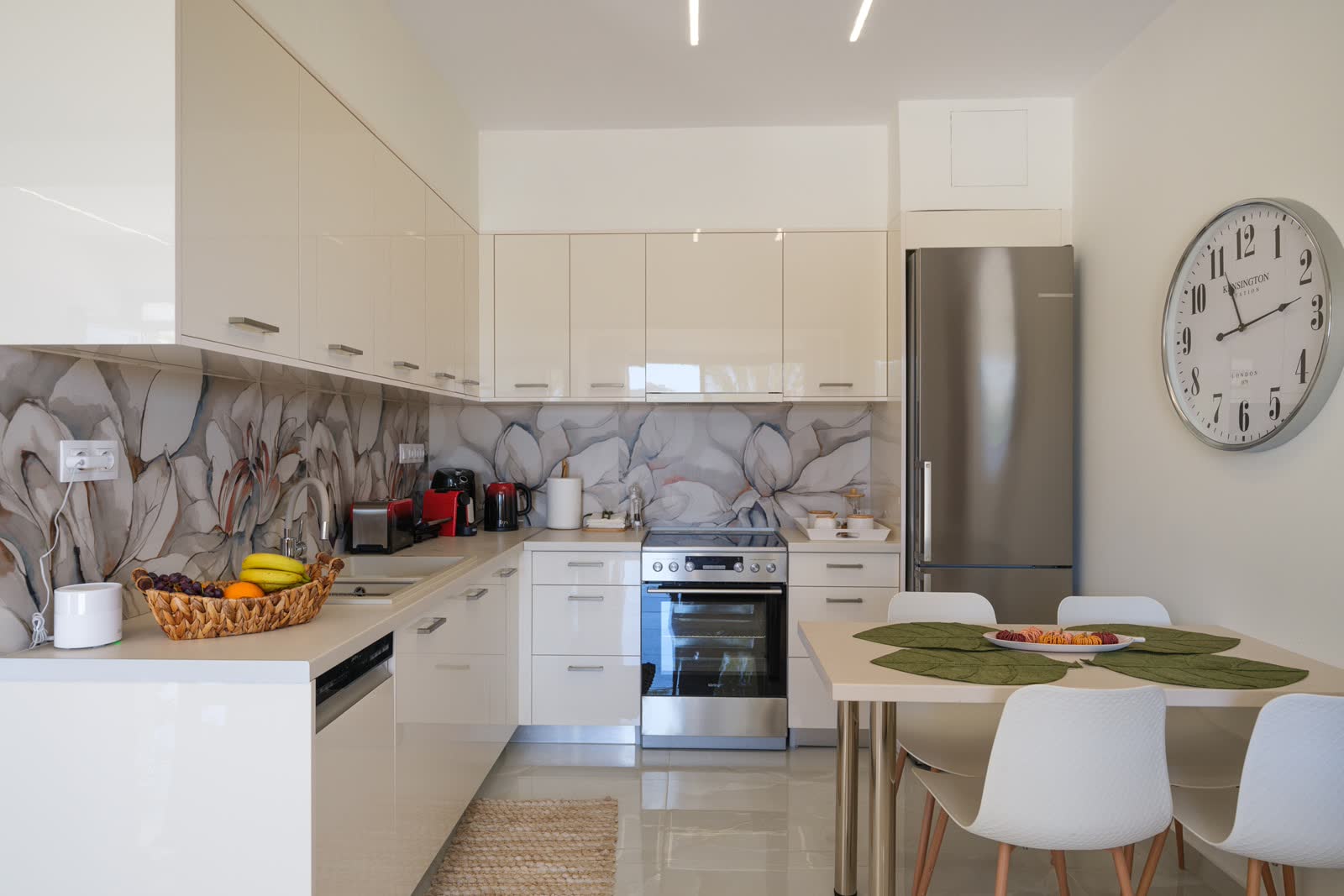 The kitchen — white cabinets, a floral splashback and the big station clock